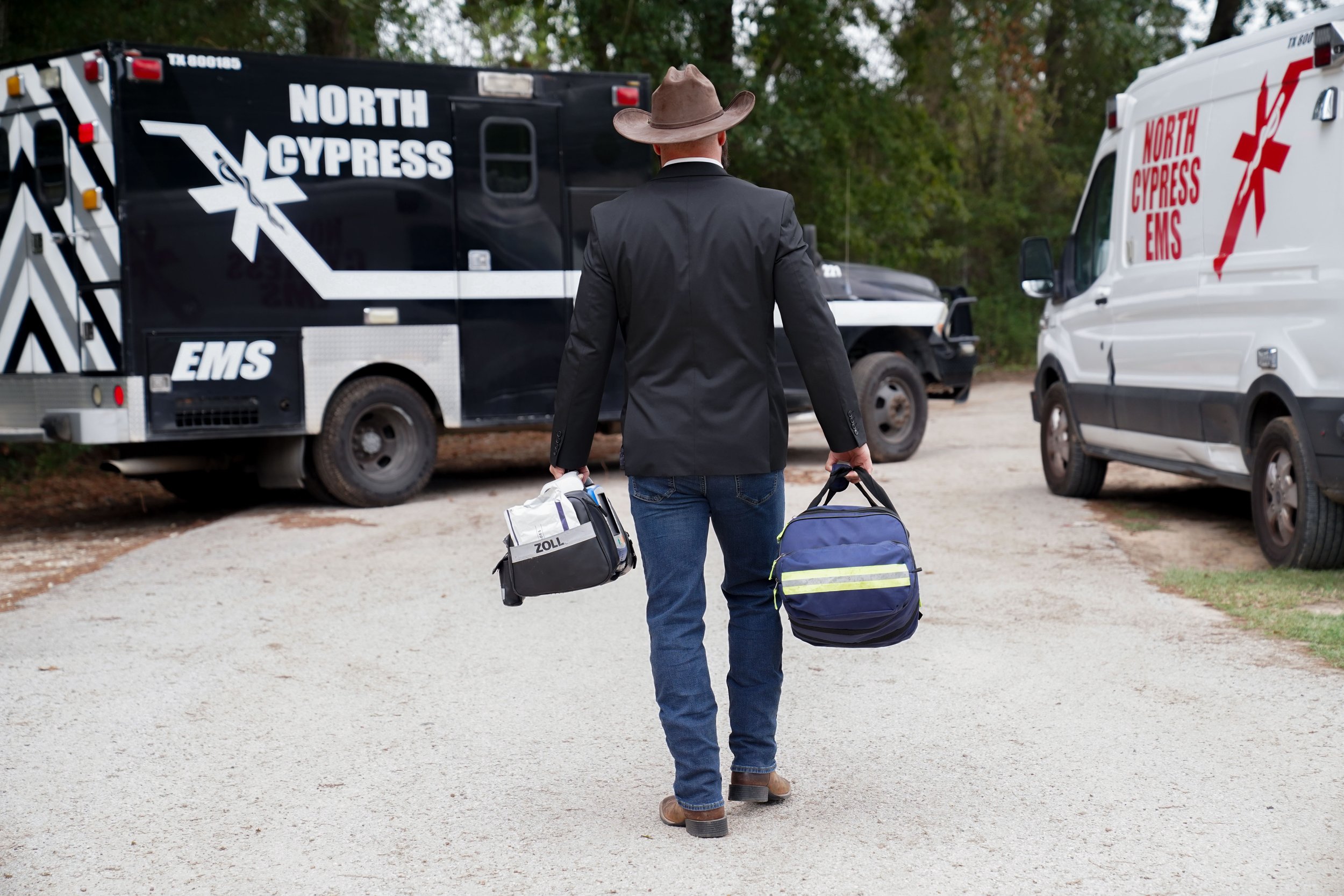 Man in Cowboy Hat walking towards ambulance holding bags
