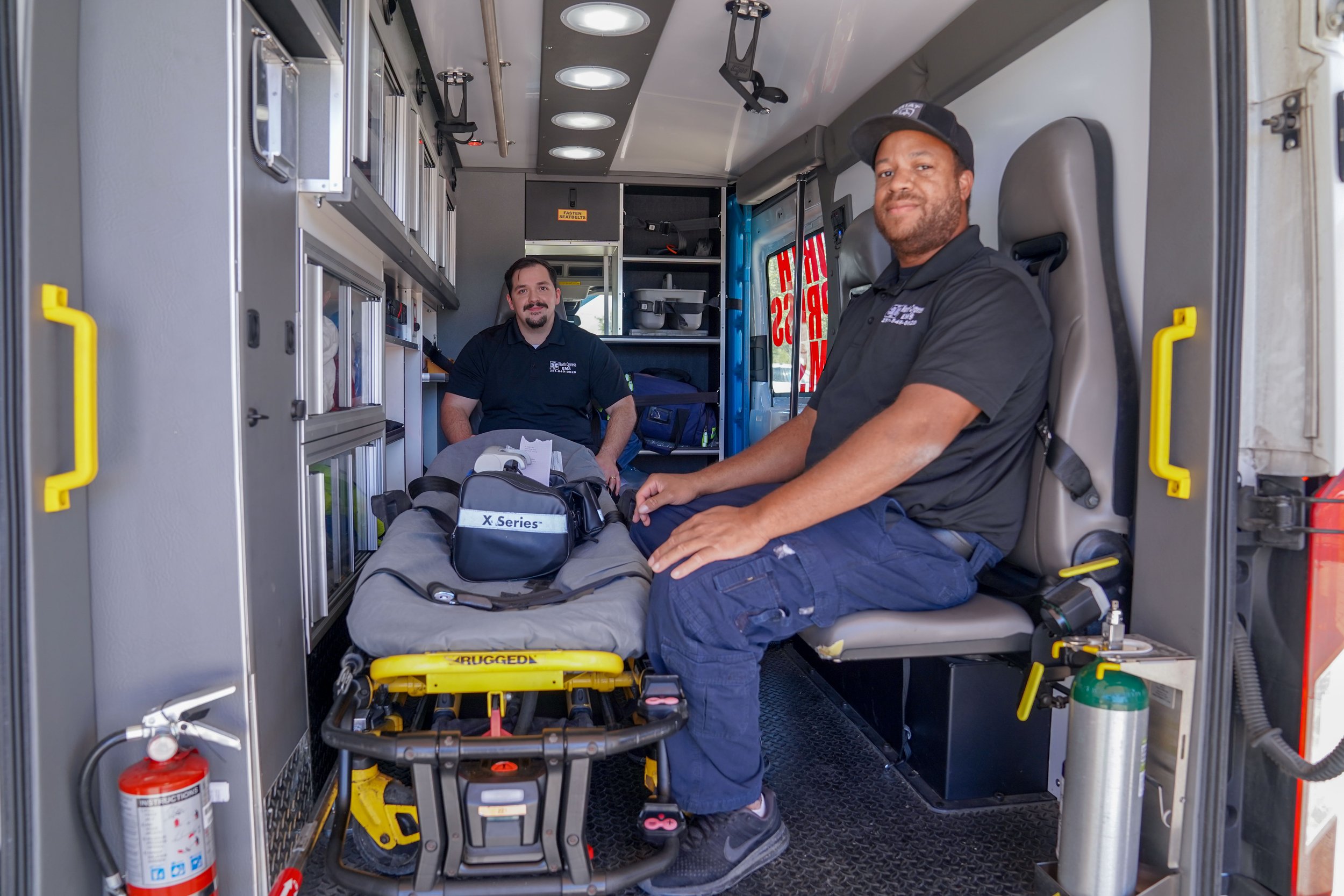North Cypress Employees sitting in the back of an ambulance with a stretcher