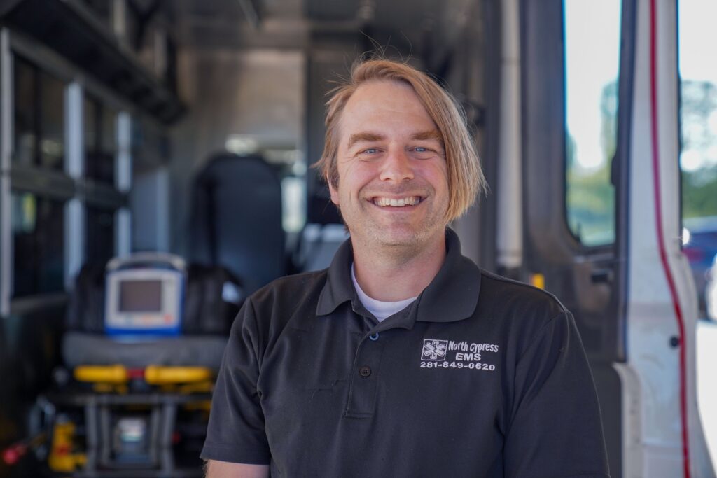 Employee standing in front of the open end of an ambulance